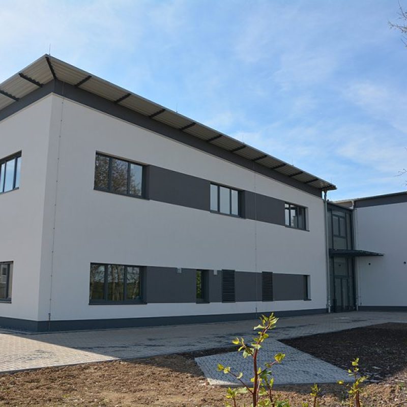 Moderne, zweigeschossige Gebäude mit weißen und grauen Fassaden, große Fenster und einem Flachdach im Freien