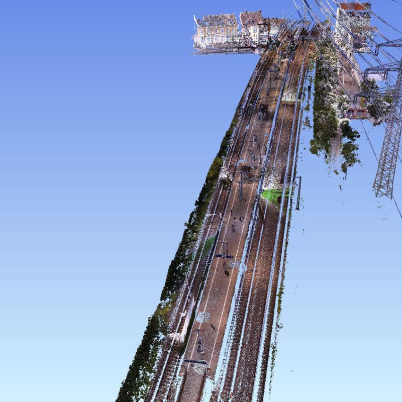 Eine schräg ausgerichtete Ansicht einer Straße mit Stromleitungen und Bäumen, umgeben von Hochhäusern im Hintergrund