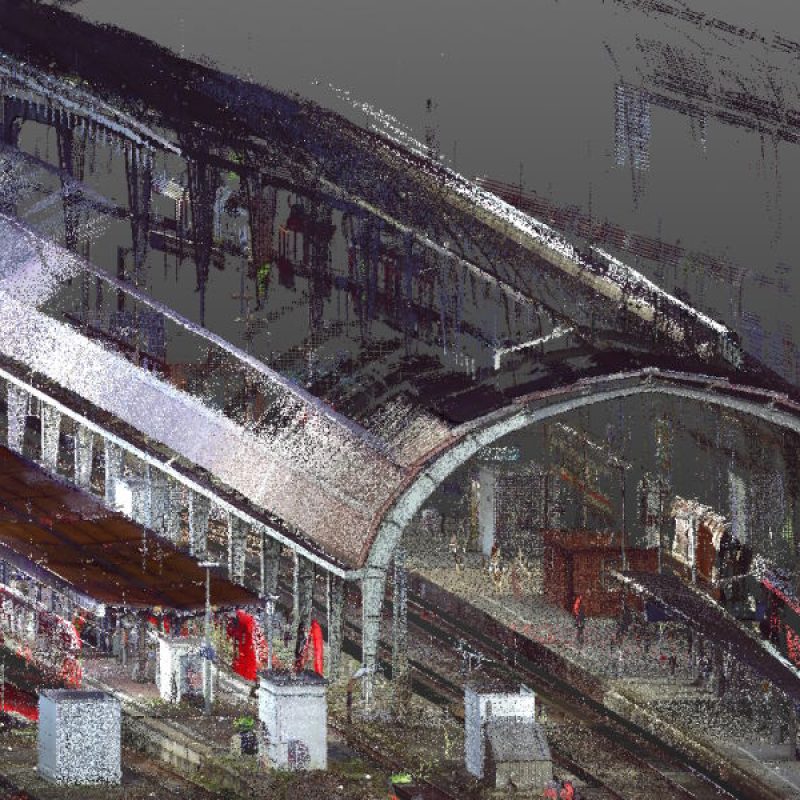 Eine digitale Darstellung eines Bahnhofs mit geschwungenem Dach, Gleisen und verschwommenen Details von Menschen und Trainern